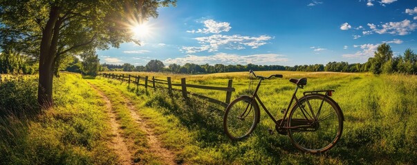Fototapeta premium A bicycle is parked in a grassy field next to a wooden fence