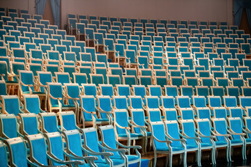 Rows of luxurious, expensive, blue chairs of classical design in the auditorium of classical academic theatre.