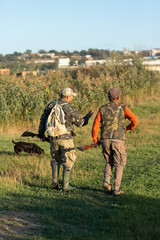 Mature hunter man holding a shotgun and walking through a field