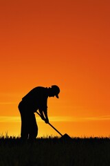 A silhouette of a worker tilling the fields at dawn.