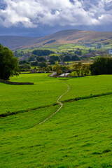 Rainclouds view across the fields to Hawes in Wensleydale, Yorkshire, UK