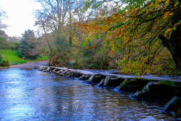 Signs of autumn at Tarr Steps clapper bridge after rain in Exmoor National Park, Somerset, UK
