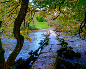 Signs of autumn at Tarr Steps clapper bridge after rain in Exmoor National Park, Somerset, UK