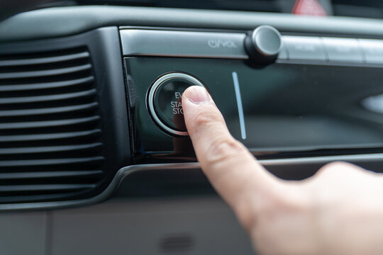 Closeup view of finger pressing the start stop button of an electric car