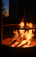 Płonące ognisko w metalowym palenisku z żeliwnym rusztem nad ogniem  © Paweł Kacperek