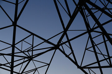 Many high-voltage power towers, silhouetted against the setting sun