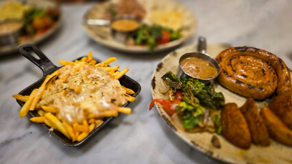 mouthwatering German worst curled up cumberland sausage meal featuring a grilled sausage, loaded cheese fries, and fresh vegetables served on a rustic plate
