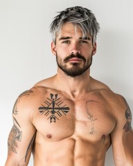 Fototapeta premium A muscular man with silver hair and intricate tattoos poses against a minimalistic background, This image can be used for fitness, lifestyle articles, or promotional content featuring body art,