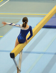 Young gymnast girl performing routine on balance beam