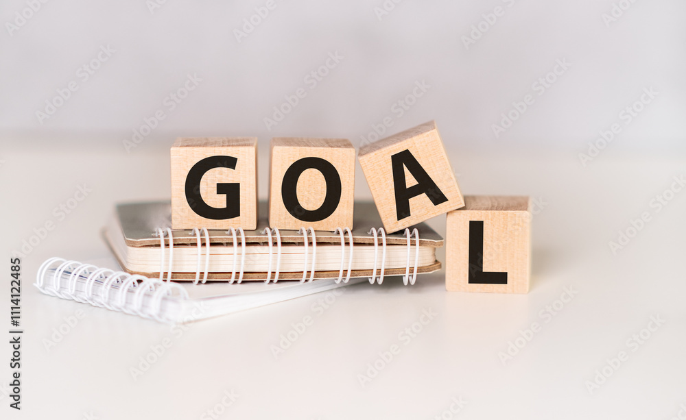 Poster four wooden cubes arranged in stack with word goal on them, space for text / image at down right cor
