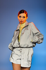 Naklejka premium A stylish young woman poses confidently against a vibrant blue backdrop.