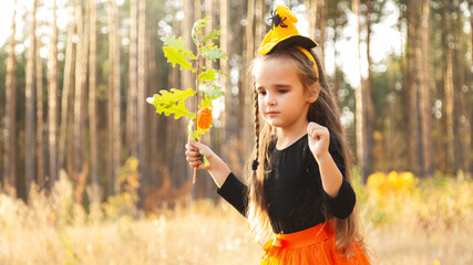 Little girl in scary witch costume at halloween celebrations party in forest. Halloween -...