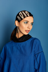 A beautiful young woman showcases her trendy attire and hair accessories in a studio setting.