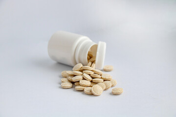 Herbal pills from a jar on a white background, top view, selective focus on the pills