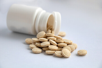 Herbal brown pills from a jar on a white background close-up upper view shot, pills on a foreground