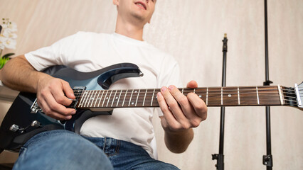 Close up young man playing string instrument, learning chords practicing music, enjoying rehearsal...