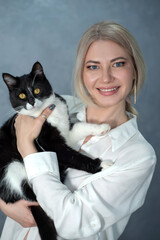 Portrait of a beautiful blonde girl holding a cat in her arms and looking at the camera.