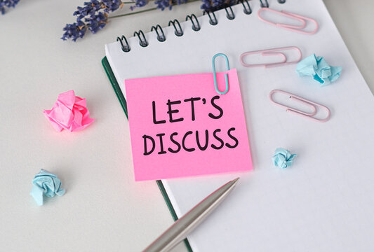 LET'S DISCUSS text on pink paper notebook on a chart with pen .