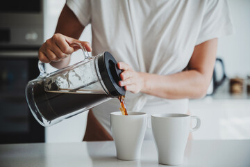 Woman Pouring Coffee from French Press in Modern Kitchen