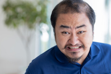 Angry Asian middle aged man with irritating expression, upset unhappy midage old real man staring...