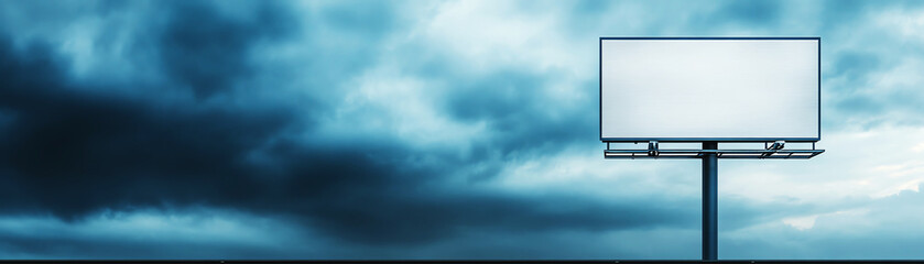 Obraz premium Solitary blank billboard against dramatic cloudy sky, for advertising concepts and urban landscape visuals.