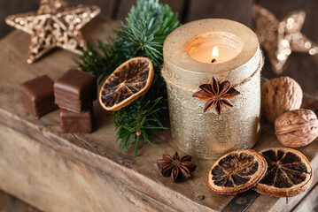 Christmas decoration with golden candle, spices and dominoes on old wood