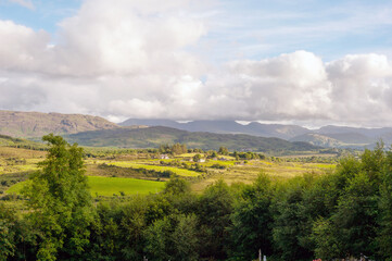 Obraz premium A beautiful landscape with a cloudy sky and mountains in the background