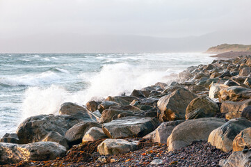The ocean is rough and the rocks are large