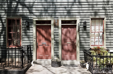 Brooklyn House. The wooden building is typical of old architecture in Brooklyn Heights, New York. Two red doors with a white trim sit in front of a gray house