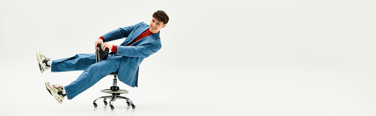 Handsome man in a stylish suit spins playfully on a chair in an airy and bright office.