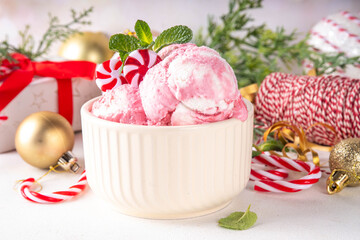 Festive Christmas holiday sweet mint candy cane peppermint ice cream in ceramic bowl, frozen creamy red and white yogurt sorbet, on Christmas New Year decorated background, copy space