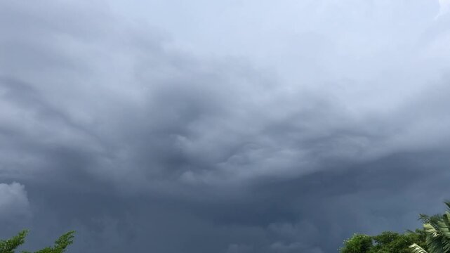 Movement of Beautiful dark rain storm clouds reveals the sun, thunderstorm in dramatic sky, with lens flare. Climate cloudscape scenic. Weather tropical summer squall.