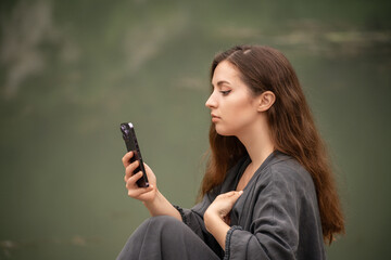 A woman is sitting on the ground and looking at her cell phone