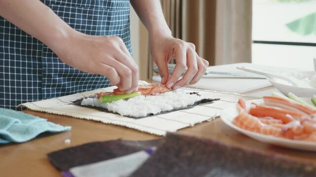 A person is making sushi on a wooden table