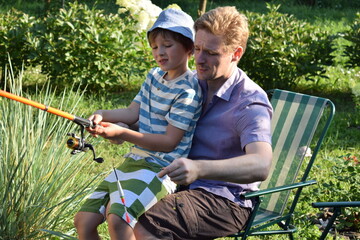 A young father and his son enjoy quality time together, fishing at a pond. The father teaches his son the basics of fishing, creating cherished memories during their outdoor family bonding experience