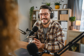 smile man radio host laugh while record podcast with woman colleague