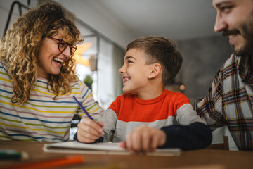 Fototapeta premium Mum and dad help their son to draw, enjoy creative hobby at home