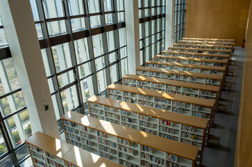 High-angle view of a modern library interior showcasing multiple rows of wooden bookshelves filled...