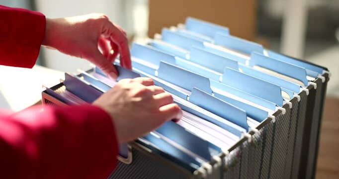A closeup view of hands meticulously arranging blue file folders within a sleek and modern office environment
