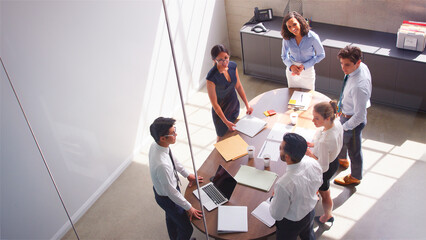 Overhead Shot Of Multi-Cultural Business Team Meeting Around Table In Modern Office Together © Monkey Business