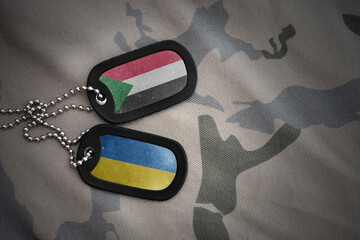 army blank, dog tag with national flag of sudan and ukraine on the khaki texture background....