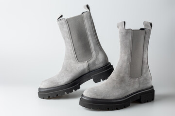 Trendy fashionable grey suede leather short women pair chelsea boots on light neutral background. Casual style.