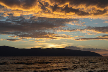 Sunset, Sky clouds over sea in the Evening with Orange, Yellow Gold sunlight at Golden hour.