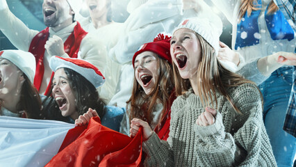 Group of young emotional sports fans, women and men, dressed in country attributes, with flag,...