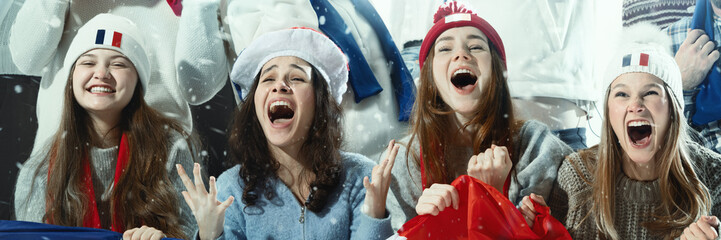 Happy and cheering female sports fans wearing hats with country flags, celebrating during sports...