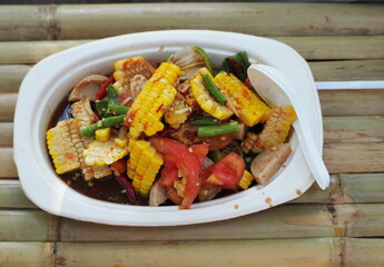 Spicy Corn Salad also known as Som tum corn salad with white pork sausage. Corn salad is a popular dish seasoned with lime, fish sauce, sugar , fermented fish, Tomatoes, and  fresh vegetables herbs  
