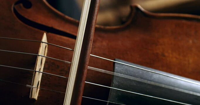 Super slow motion macro of master luthiers hands draw bow across strings of handmade violin at 1000 fps. Each movement showcase precision and artistry in both playing and craftsmanship of instrument