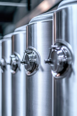 Steel tank barrels line up in a row, brewery or wine cellar, manufacturing process of alcohol production, copy space background