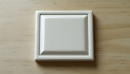 White square button on light wood surface.