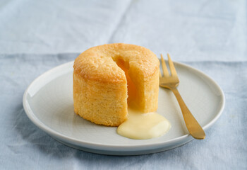 White chocolate fondant or lava cake dessert in a plate, on a light blue background. Copy space, closeup view.